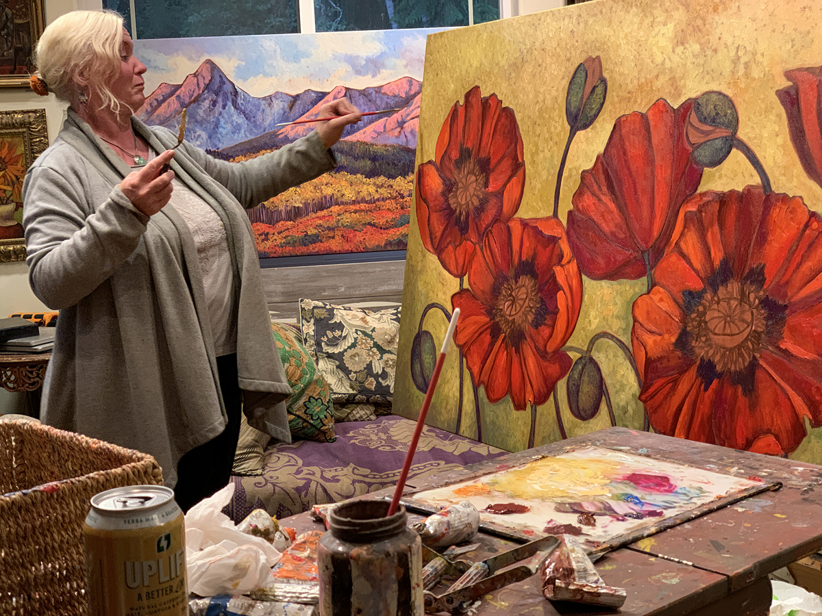 Maia Leisz in her studio, painting the Red Poppies commission with Singing Desert in the background
